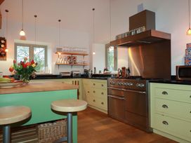 A kitchen with a stove, sink, and bar stools at Kerslake House in Crafthole