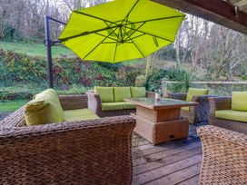 An outdoor patio with seating and a table covered by an umbrella at Kerslake House in Crafthole