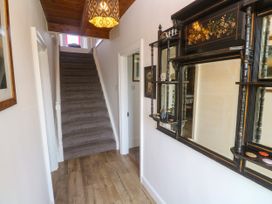 A hallway with a staircase and a decorative shelf at Halwyn Farm in Helston