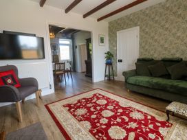 A living room with a green sofa and television at Halwyn Farm in Helston