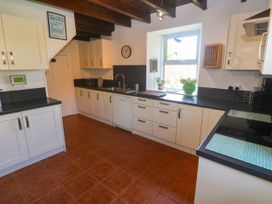 A kitchen with cabinets, sink, and window at Halwyn Farm in Helston