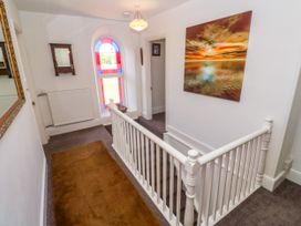 A hallway with a staircase and window at Halwyn Farm in Helston