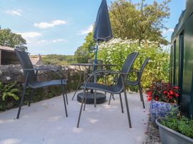 A table with chairs and an umbrella in an outdoor seating area at Halwyn Farm in Helston