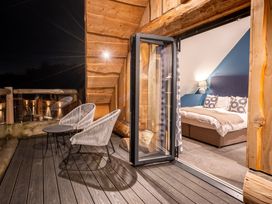 A bedroom with a bed and chairs on a balcony at The Lookout in Addingham