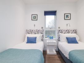 A bedroom with two beds and a bedside table at Pentewan in Redruth