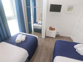 A bedroom with two beds, towels, a television and a mirror at Pentewan - 67 Portreath