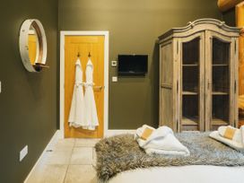 A bedroom with bathrobes hanging on a door and a cabinet at Bears Den Addingham