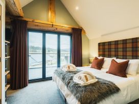 A bedroom with a bed and windows at Keepers Cabin in Addingham