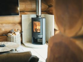 A living room with a fireplace and a wood basket at Apres Ski in Addingham