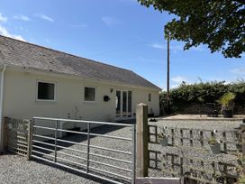 An outdoor view of a house with a gate and gravel area at Swallow Cottage in Llangefni