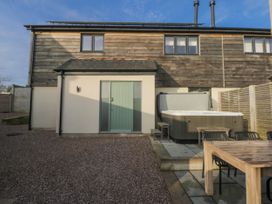 An outdoor space with a hot tub and dining table at Bell House in Llanfechell