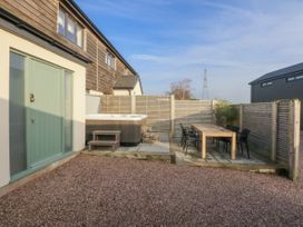 A garden with a hot tub and dining table at Bell House in Llanfechell