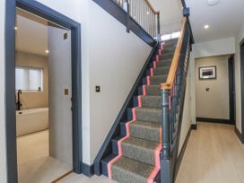 A hallway with stairs leading up and a bathroom door at Bell House in Llanfechell