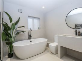 A bathroom featuring a bathtub, toilet, and sink at Bell House in Llanfechell