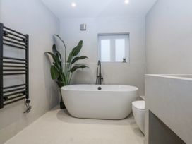 A bathroom with a bathtub, toilet and a towel warmer at Bell House in Llanfechell