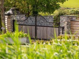A garden with a gate and stone wall at Bell House in Llanfechell