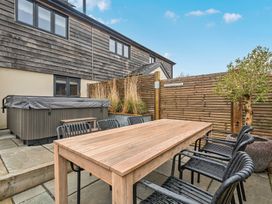 A garden with a table and chairs next to a hot tub at Bell House in Llanfechell