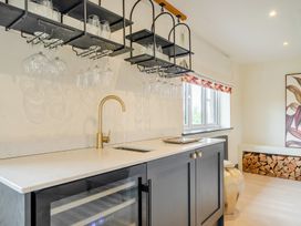 A kitchen with a sink, wine cooler and shelves holding glasses at Bell House Llanfechell