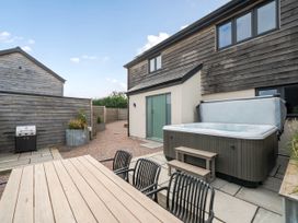 An outdoor area with a hot tub and dining set at Bell House in Llanfechell