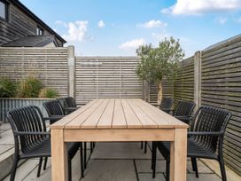 An outdoor dining area with a wooden table and black chairs at Bell House in Llanfechell