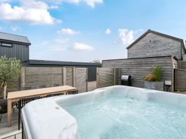 An outdoor space with a hot tub and dining table at Bell House in Llanfechell