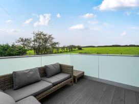 A balcony with an outdoor sofa overlooking green fields at Bell House in Llanfechell