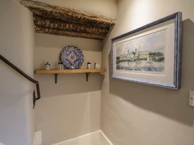 A staircase with a shelf, decorative plate, and framed painting at 23 New Church Street in Tetbury