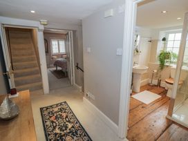 A hallway with a staircase and doors to the bathroom and bedroom at 23 New Church Street Tetbury