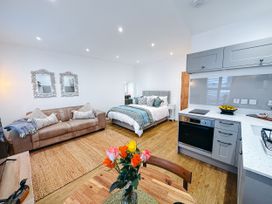 A studio apartment with a bed, sofa, and kitchen area at Ammil Bespoke