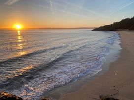 A beach with ocean waves and a sunset in the background at Ammil Bespoke 