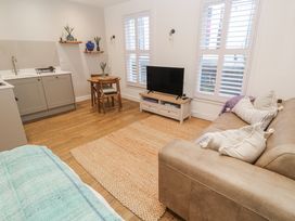 A living room with a kitchen area and television at Ammil Bespoke St Ives