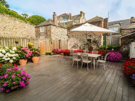 A garden with flower pots and a dining table under an umbrella at Ammil Bespoke in St Ives