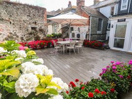 An outdoor area with a table and chairs shaded by an umbrella at Ammil Bespoke in St Ives