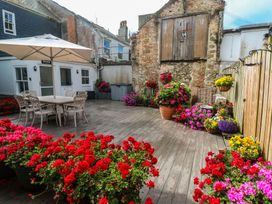A garden with a table and chairs surrounded by flowers at Ammil Bespoke in St Ives