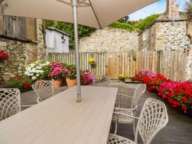 An outdoor dining area with a table and chairs surrounded by flowers at Ammil Bespoke St Ives
