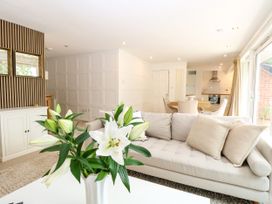 A living room with a sofa and vase of flowers at Three Ways in South Lopham near Garboldisham
