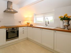 A kitchen with an oven, sink, and flowers at Three Ways in South Lopham near Garboldisham