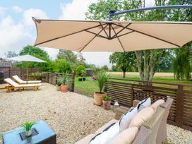 An outdoor seating area with sun loungers and an umbrella at Three Ways South Lopham near Garboldisham