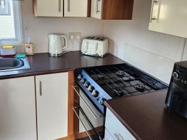 A kitchen with a sink, kettle, toaster, gas stove, and coffee maker at Elm 33 in Scarborough