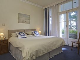 A bedroom with a bed, nightstand, and curtains at 4 Ringrone, Salcombe