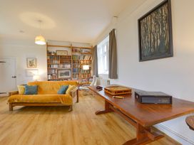 A living room with a sofa, bookshelf, and table at School House in Ivybridge