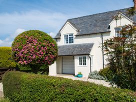 A house with a flowering shrub and green bushes at Glencoe Cottage in Broadway