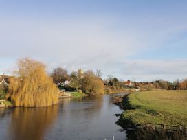 A river with a willow tree and buildings near the water at Glencoe Cottage in Broadway