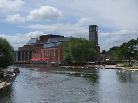 A building by the river with trees and clouds at Glencoe Cottage in Broadway