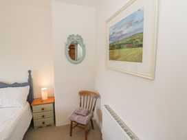 A bedroom with a bed and chair at Glencoe Cottage in Broadway