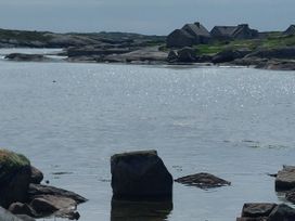A landscape with water, rocks, and houses at Tigh Marie 