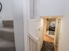 A hallway with stairs leading up and a view into the living room at Newlands Fell House in Newlands near Keswick
