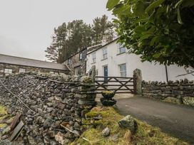 An outdoor view of a house with a stone wall and gate at Newlands Fell House near Keswick