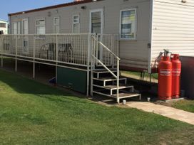 An outdoor view of a mobile home with steps and gas cylinders at Gannet 18 (G18) Bridlington