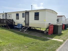 A static caravan with a blue bench and gas cylinders at Gannet 19 (G19) Bridlington
